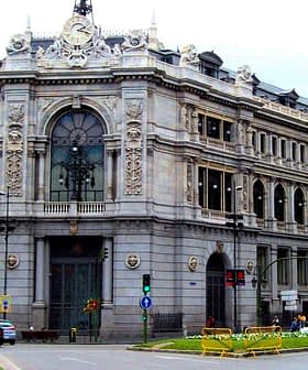 A large historic building in Madrid featuring ornate architectural details and a clock on the facade. - Olive Oil Times