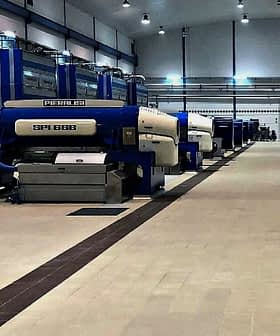 Industrial olive oil processing machines arranged in a facility with blue and white colors. - Olive Oil Times