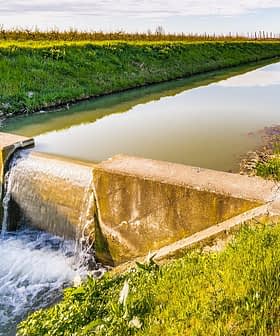 Betonkonstruktion, die den Wasserfluss in einen Kanal leitet, der auf beiden Seiten begrünt ist. - Olive Oil Times