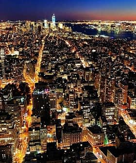 Pogled iz zraka na obzorje New Yorka, osvetljeno ponoči z mestnimi lučmi in vidnimi zgradbami. - Olive Oil Times