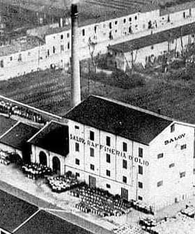 Image en noir et blanc du bâtiment de l'usine d'huile d'olive Salov avec une haute cheminée. - Olive Oil Times