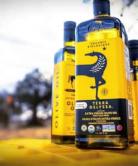 Tri steklenice ekološkega ekstra deviškega oljčnega olja Terra Delyssa z rumeno etiketo z logotipom konja. - Olive Oil Times