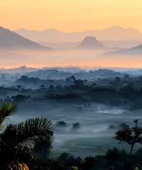 Un paysage brumeux avec des montagnes et des vallées au lever du soleil avec une lumière douce et du brouillard. - Olive Oil Times