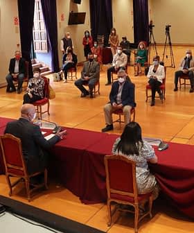Skupina ljudi sedi v konferenčni sobi med sestankom z mizo v ospredju. - Olive Oil Times