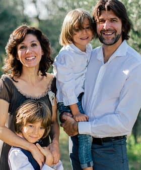 A family of four posing together in an olive grove, with two adults and two children. - Olive Oil Times