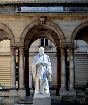 Wit standbeeld van een historische figuur op de binnenplaats van het gebouw van het Collège de France. Olive Oil Times