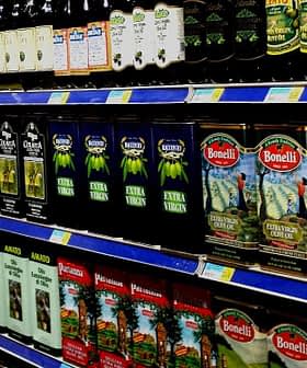 Uno scaffale di un supermercato che espone varie marche di olio d'oliva in bottiglie e cartoni. - Olive Oil Times