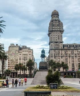 Statue d'un cavalier située sur la Plaza Independencia, entourée de palmiers et de bâtiments à Montevideo. - Olive Oil Times
