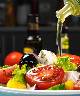 Ένα μπολ με φρέσκια σαλάτα που περιχύνεται με ελαιόλαδο, με ντομάτες, μαρούλι και ελιές. - Olive Oil Times