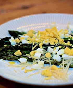 Teller mit gekochtem Spargel, garniert mit gehacktem Ei und geriebenem Käse. - Olive Oil Times