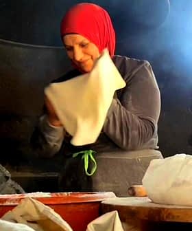赤いスカーフを巻いた女性がキッチンで生地を準備しています。 - Olive Oil Times