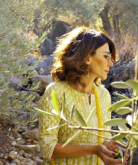 戴眼镜的女人站在自然环境中的橄榄树中间。 - Olive Oil Times