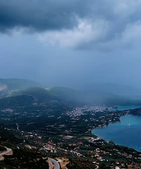 Un paysage côtier avec des montagnes, une baie et un ciel nuageux au-dessus de l'eau. - Olive Oil Times