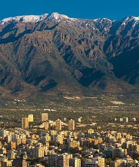 Una catena montuosa con cime innevate sullo sfondo e un paesaggio urbano in primo piano. - Olive Oil Times