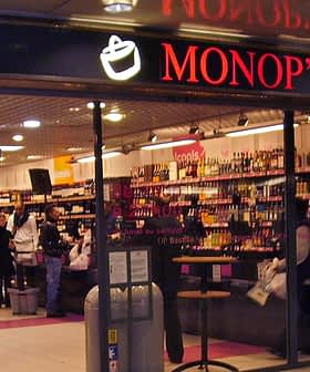 Ingresso di un supermercato Monop' con scaffali pieni di prodotti vari. Olive Oil Times