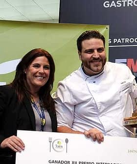 Chef-kok houdt een prijs vast terwijl hij poseert met een vrouw op een gastronomisch evenement. Olive Oil Times