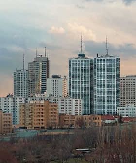 Paisaje urbano de Teherán con la Torre Milad y varios edificios bajo un cielo nublado. Olive Oil Times