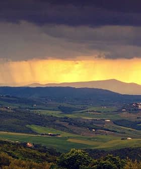 Vista panorámica de colinas onduladas con nubes oscuras y luz del sol abriéndose paso en la distancia. Olive Oil Times
