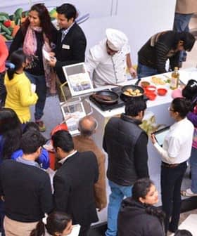 Group of people participating in an olive oil tasting event with various olive oil samples displayed. - Olive Oil Times
