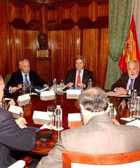 Groupe de fonctionnaires assis autour d'une grande table de conférence lors d'une réunion. - Olive Oil Times