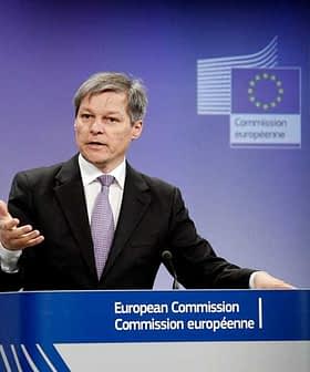 Moški, ki govori na odru med tiskovno konferenco Evropske komisije z emblemom EU v ozadju. - Olive Oil Times