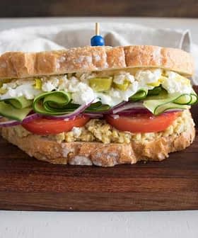 Tam tahıllı ekmekle yapılmış, içinde yumurta salatası, salatalık, domates ve turşu bulunan bir sandviç. Olive Oil Times