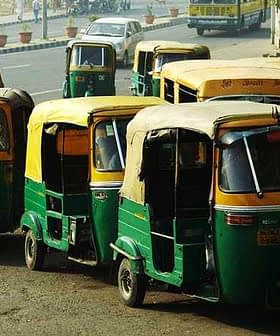 Multiple green and yellow auto rickshaws parked on a street in an urban area. - Olive Oil Times