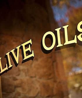 Gros plan d'un panneau sur lequel est écrit « Huiles d'olive » en lettres dorées sur fond sombre. - Olive Oil Times