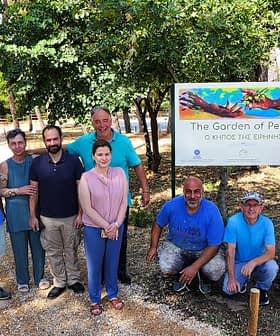 'Barış Bahçesi' yazılı bir tabelanın önünde poz veren dokuz kişilik bir grup. - Olive Oil Times