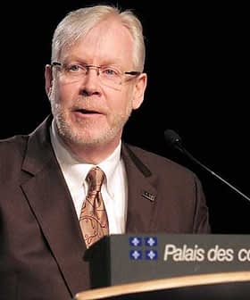 Un uomo con gli occhiali parla da un podio con un cartello che recita "Palais des congrès de Montréal". - Olive Oil Times