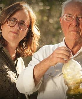 Ein Mann und eine Frau stehen zusammen, wobei der Mann eine Olivenölflasche in der Hand hält. - Olive Oil Times