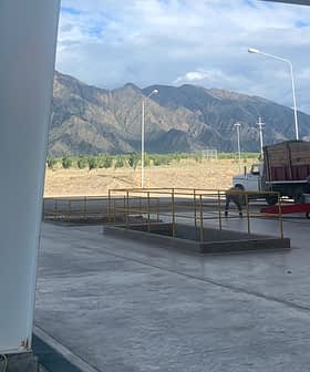 一辆卡车停在装卸区，背景中可见群山。 - Olive Oil Times