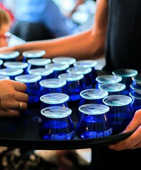 Un plateau contenant plusieurs verres bleus remplis d'huile d'olive servis lors d'un événement. - Olive Oil Times