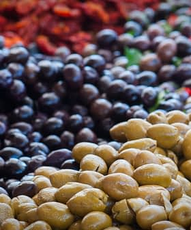 Esposizione di olive verdi e nere disposte in un ambiente di mercato. - Olive Oil Times