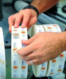 製造現場で粘着ラベルのロールにラベルを貼る作業者。 - Olive Oil Times