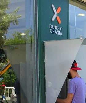 在哈尼亚银行使用带有明显银行标志的 ATM 机的人。 - Olive Oil Times