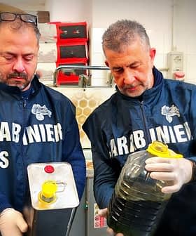 Zwei Männer in Uniform halten einen Metallbehälter und eine mit Öl gefüllte Plastikflasche. - Olive Oil Times