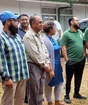 A group of diverse individuals standing together outdoors, wearing casual clothing and engaged in conversation. - Olive Oil Times