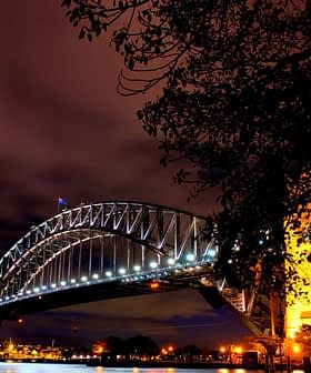 Сіднейський міст-Харбор-Брідж, освітлений вночі з чистим небом і хмарами на задньому плані. - Olive Oil Times