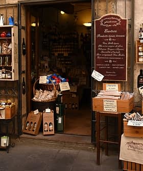 Entrada de uma loja de alimentos especializados em comida italiana com vários produtos expostos do lado de fora. - Olive Oil Times