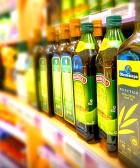 Différentes bouteilles d'huile d'olive exposées sur une étagère de magasin dans une allée d'épicerie. - Olive Oil Times