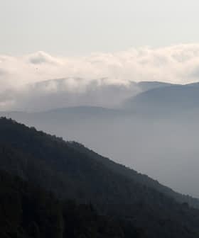 Paesaggio montuoso stratificato con nebbia e nuvole che nascondono le cime sullo sfondo. - Olive Oil Times