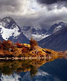 Paesaggio montano caratterizzato da cime e un lago che riflettono lo scenario del Parco Nazionale Torres del Paine. - Olive Oil Times