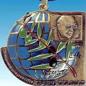 Medal featuring a globe design with an olive branch and a portrait of Mario Solinas. - Olive Oil Times