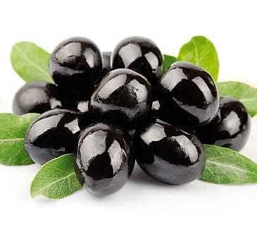 A cluster of black olives resting on green leaves, showcasing their glossy surface. - Olive Oil Times