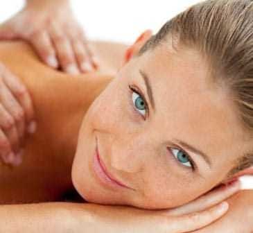 A woman with blue eyes and light brown hair lying on a massage table during a massage session. - Olive Oil Times