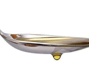 A silver spoon with a drop of olive oil resting at the tip of the spoon. - Olive Oil Times