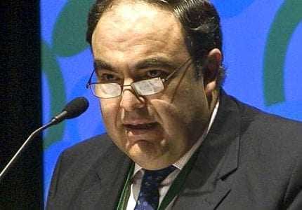 A man wearing glasses speaking at a podium during a conference or event. - Olive Oil Times