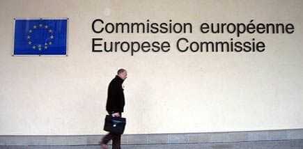 A person walking past the European Commission signage with the EU flag displayed on the wall. - Olive Oil Times