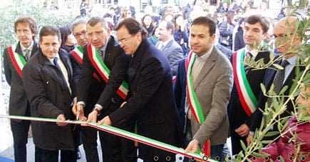 Group of officials participating in a ribbon cutting ceremony, wearing sashes and standing together. - Olive Oil Times